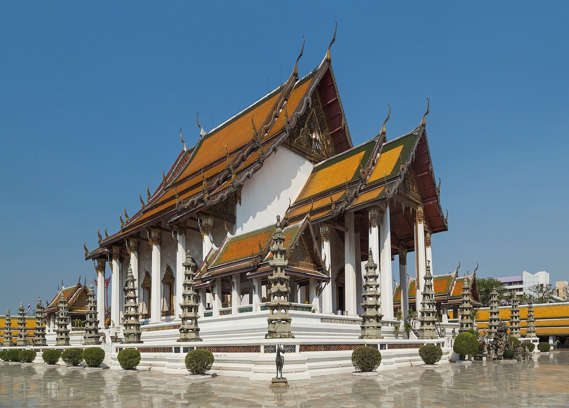 Sala principale del Wat Suthat a Bangkok con architettura tradizionale thailandese e tetto arancione decorato sotto il cielo azzurro