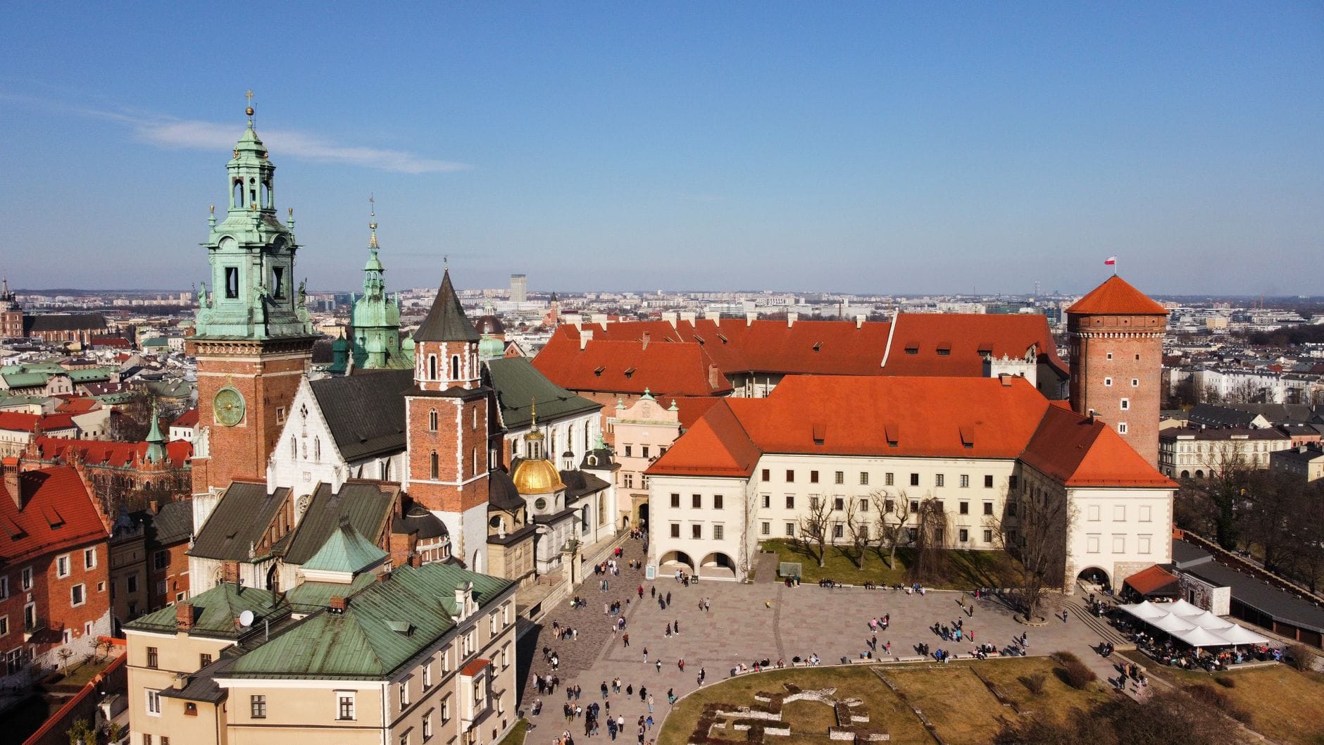 มุมมองทางอากาศของปราสาทและมหาวิหาร Wawel พร้อมลานภายในที่คึกคักและฝูงชนที่มองเห็นได้ในวันที่แดดออกที่เมือง Kraków
