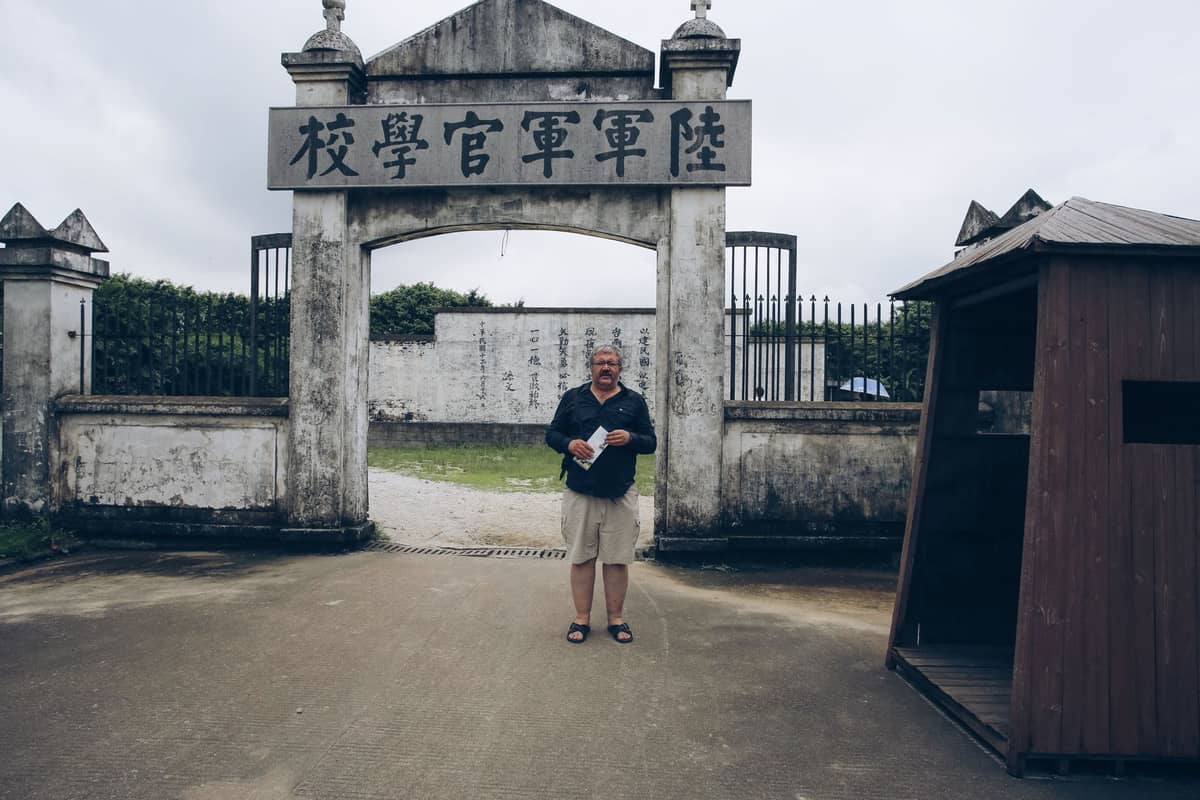 Front gate of the Whampoa Military Academy Memorial Site with Chinese characters above the arch and a visitor standing in front.
