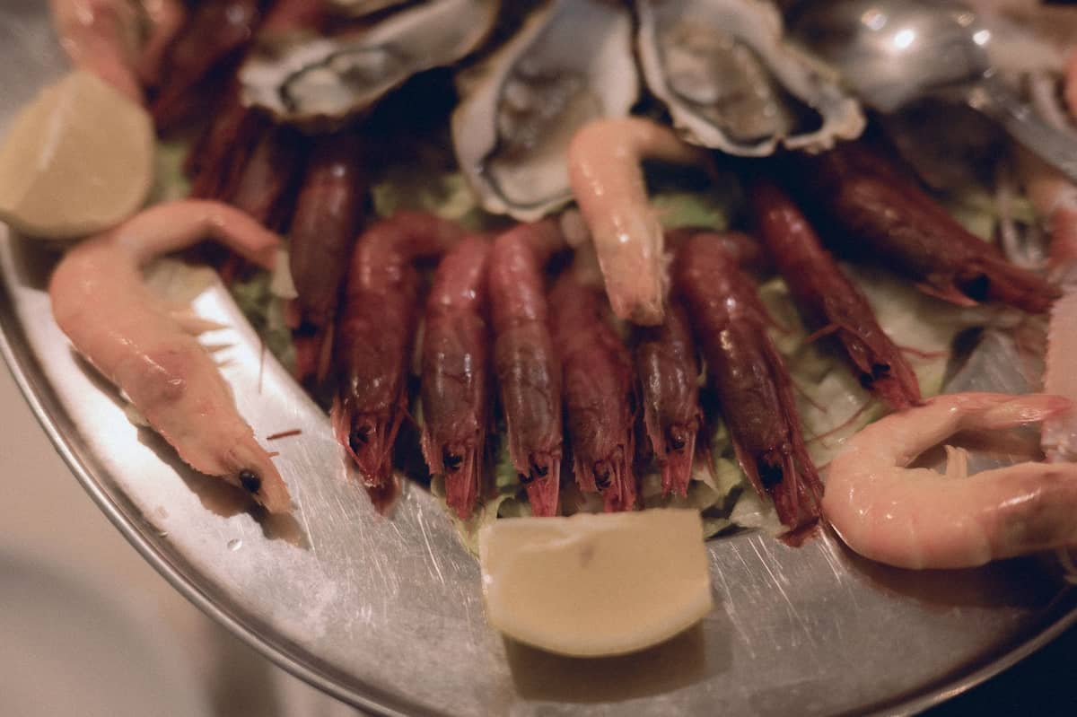 Piatto con gamberi assortiti e ostriche su un letto di verdure e spicchi di limone, che mette in risalto i frutti di mare freschi australiani.