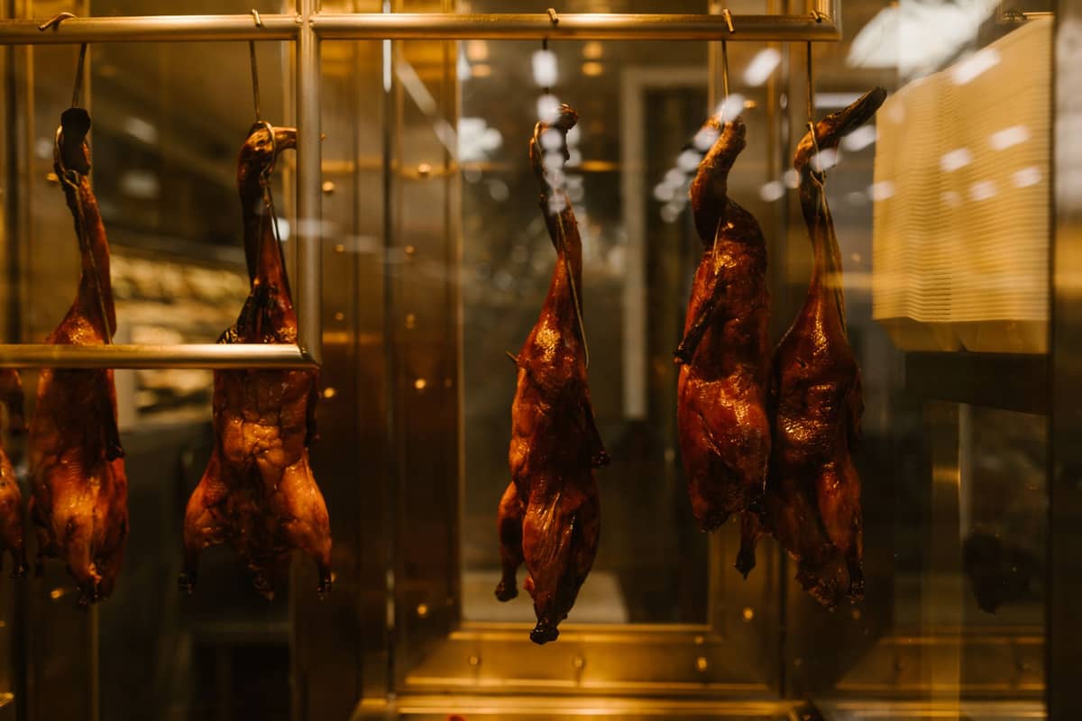 Mehrere gebratene Enten hängen in einer beheizten Restaurant-Vitrine, bereit zum Servieren in einem Lokal im Beijing-Stil.
