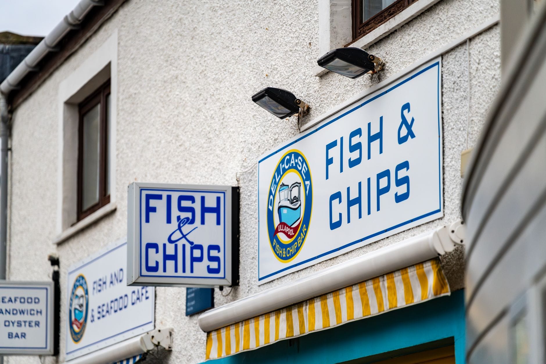 Esterno luminoso e chiaro di un negozio di fish and chips con insegne ben visibili, che suggerisce un classico chippy britannico, probabilmente a Brighton.