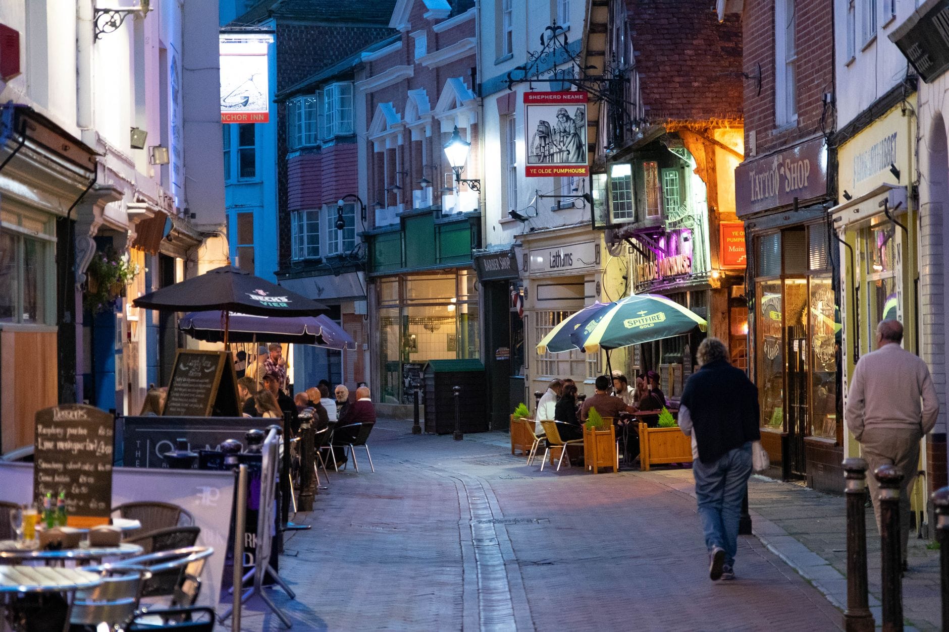 Incantevole strada pedonale alla luce della sera, fiancheggiata da ristoranti indipendenti, caffè e persone che cenano all'aperto, che rispecchia i quartieri gastronomici di Brighton.