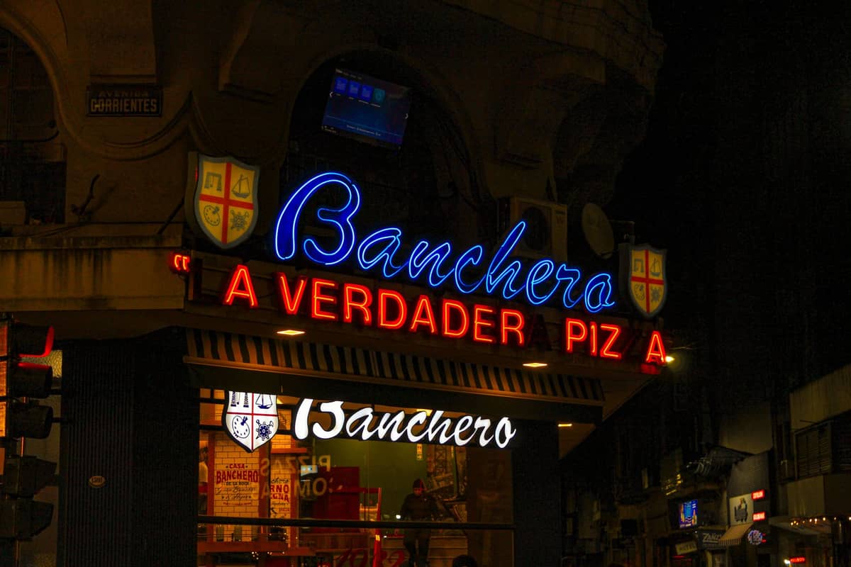 ด้านหน้าร้านพิซซ่า Banchero ที่สว่างไสวด้วยไฟนีออน ร้านพิซซ่าชื่อดังในบัวโนสไอเรสที่มีมรดกอิตาเลียน ถ่ายในเวลากลางคืน