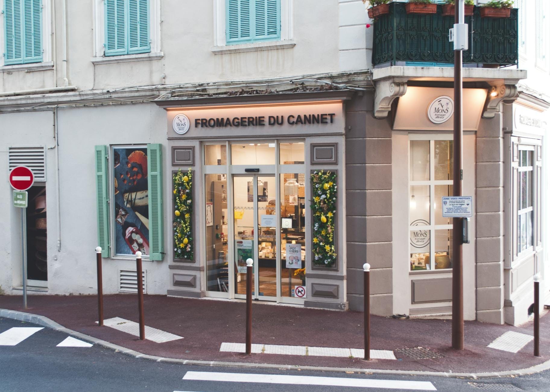 Uma charmosa queijaria francesa, a Fromagerie Du Cannet, com fachada decorada com flores, expressando a cultura gastronômica provençal de Cannes.