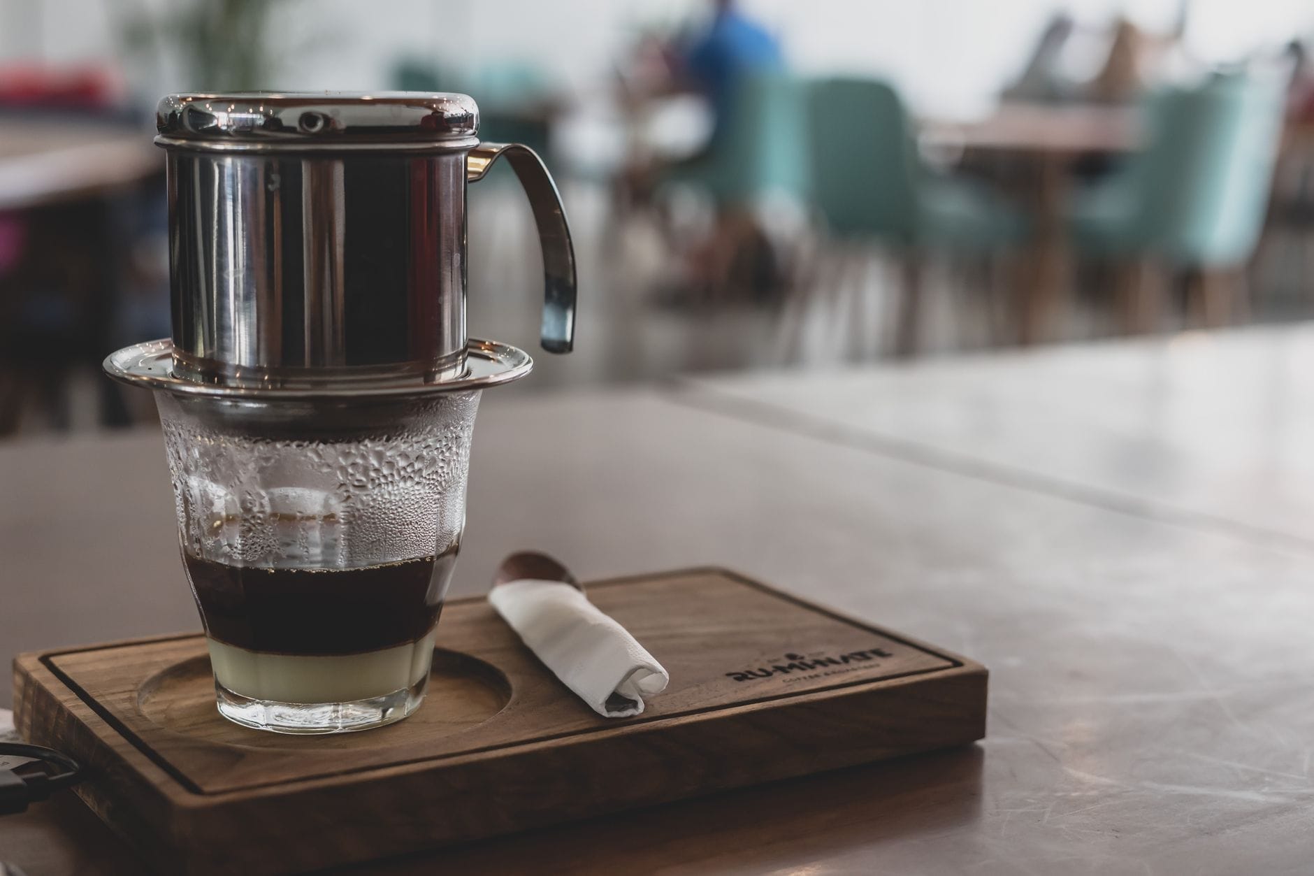 กาแฟเวียดนามที่หยดผ่านกรองพินลงในแก้วที่มีนมข้นหวานบนถาดไม้ในคาเฟ่สมัยใหม่