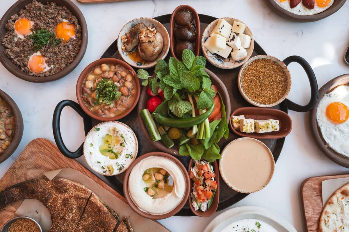 Eine große Platte mit traditionellem nahöstlichem Mezze: Hummus, Labneh, gebratene Eier, Gemüse, frische Kräuter, Fladenbrot und verschiedene lokale Dips – ideal zum Kennenlernen der emiratischen und regionalen Küche.