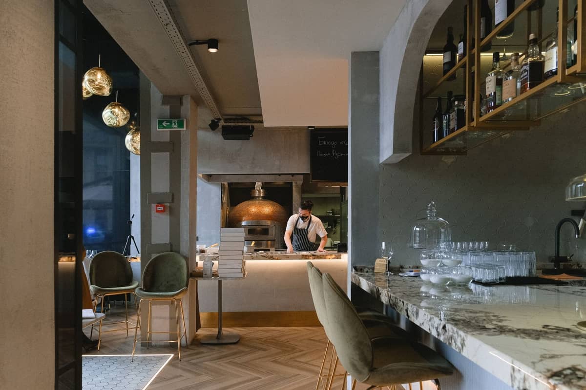 Interno di ristorante contemporaneo a Dublino con moderno bancone in marmo, cucina a vista con chef, arredamento elegante e illuminazione d'atmosfera.