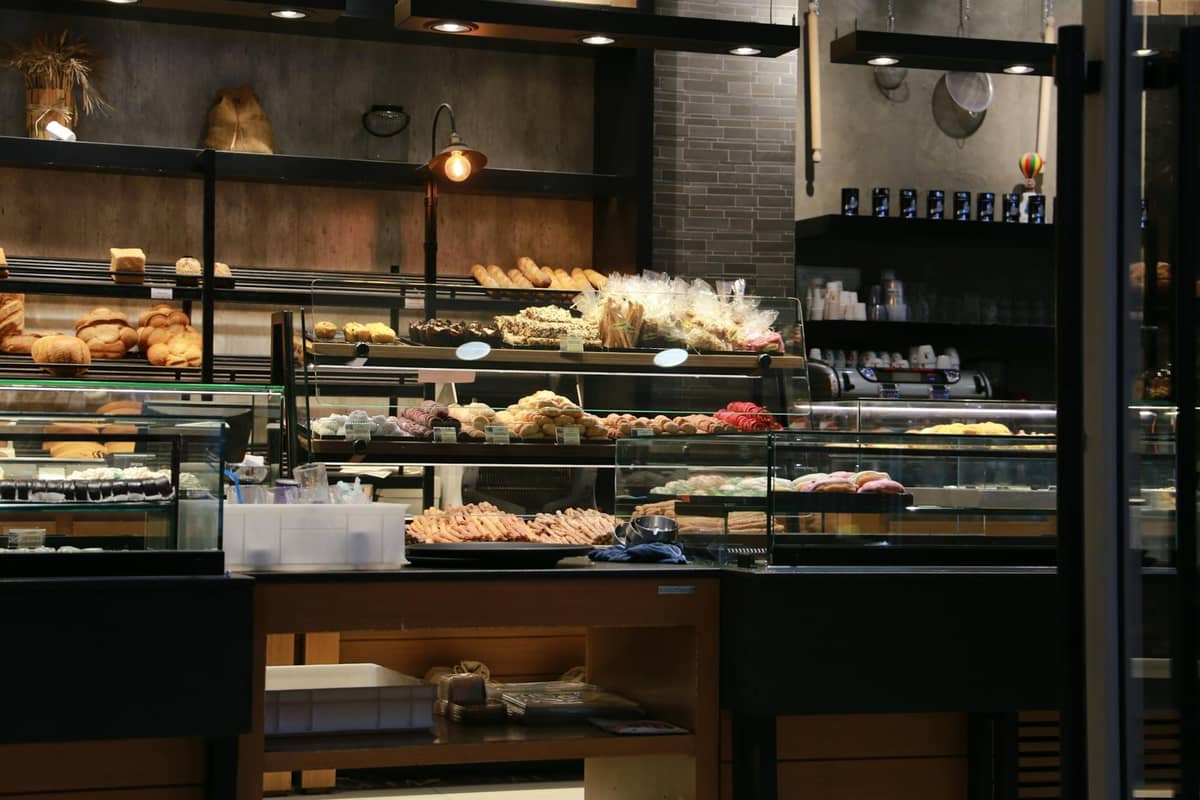 Interior of a bakery with glass display cases full of breads and pastries, warm lighting, and rustic decor.