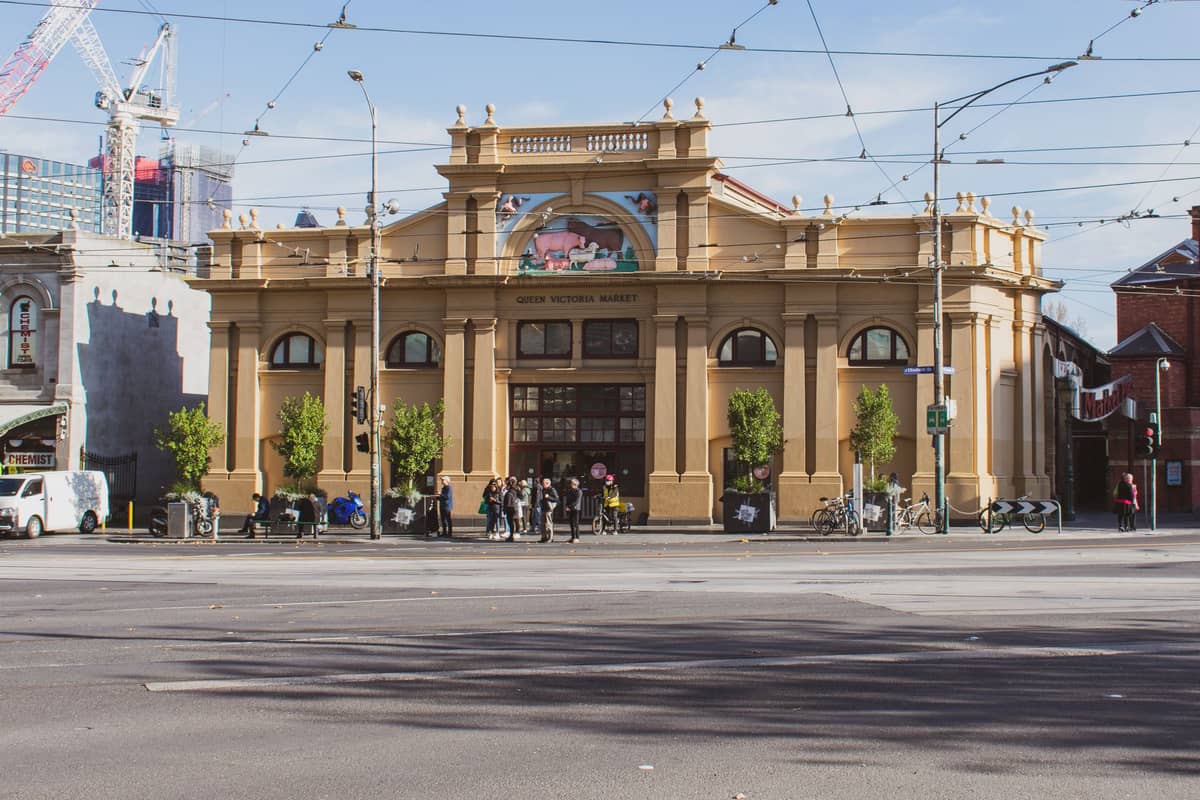 Widok z przodu budynku Queen Victoria Market z ludźmi i rowerami na chodniku w Melbourne, Australia