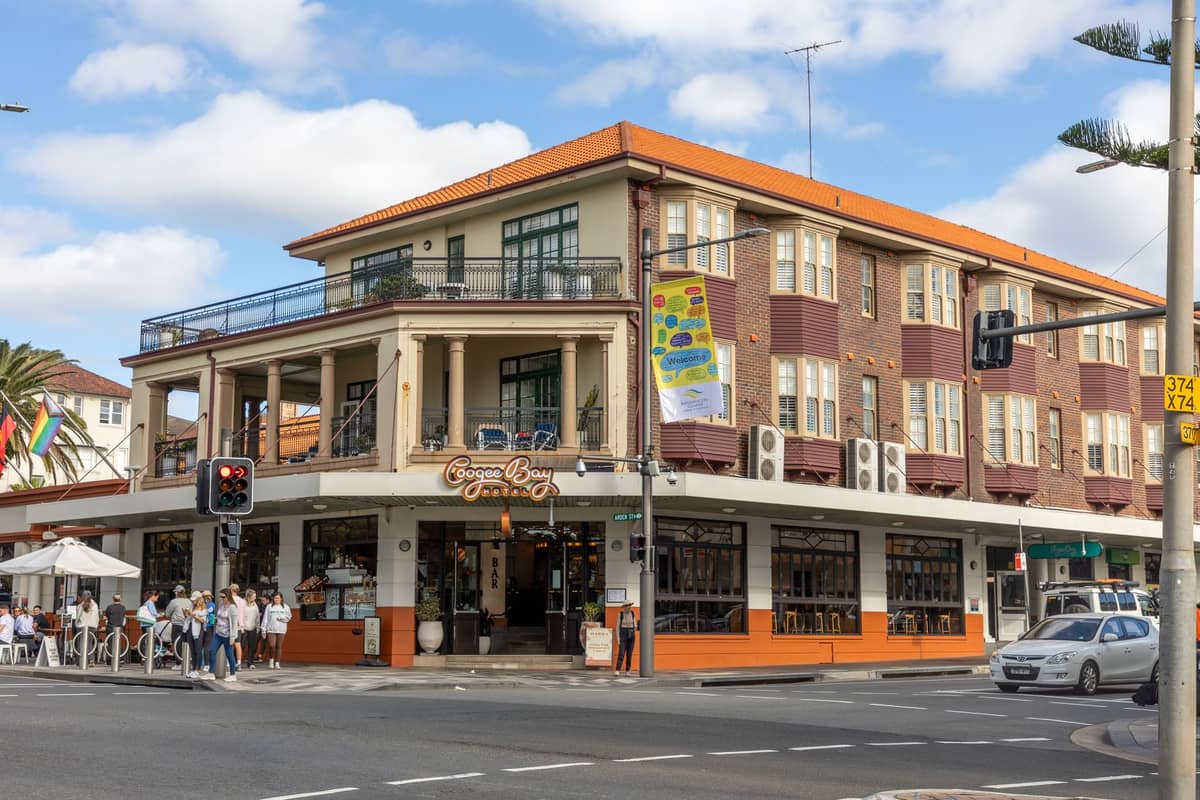 Street corner in Sydney with a bustling café and people outside, typical of a busy multicultural food neighbourhood.