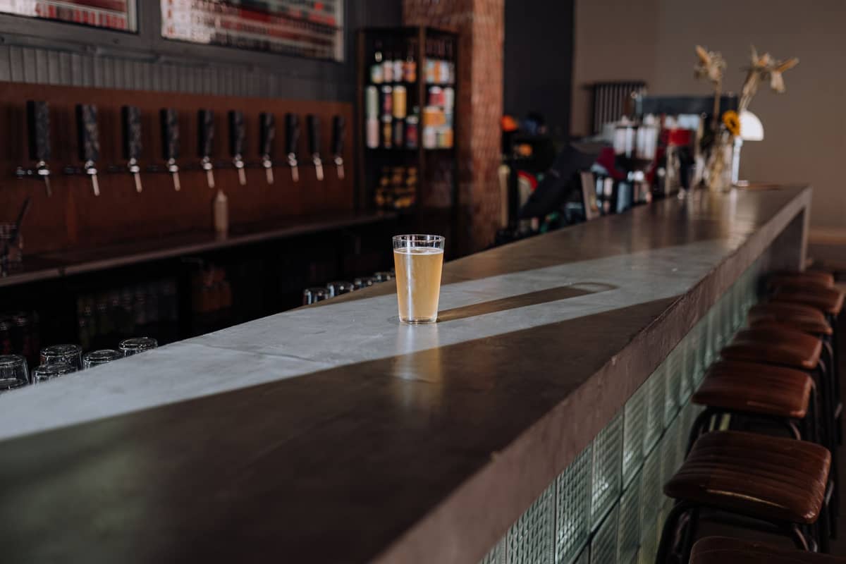 Moderner Bar mit warmem Licht, einer Reihe von Zapfhähnen und einem Glas Lager auf dem Tresen, der an Tallinns Craft-Beer-Szene erinnert.