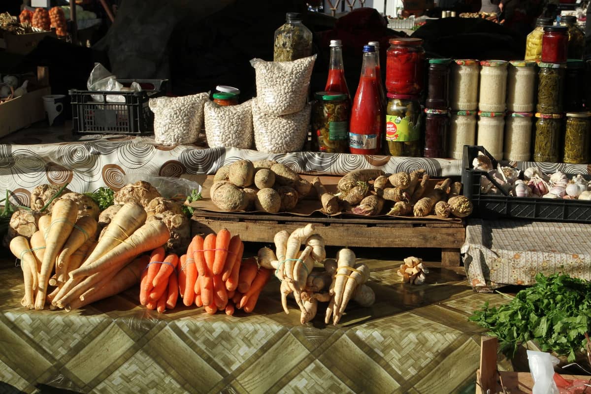 Saisonales Wurzelgemüse, Karotten, Pastinaken, Einmachgläser und Bohnen zum Verkauf im Freien an einem Bauernmarktstand.