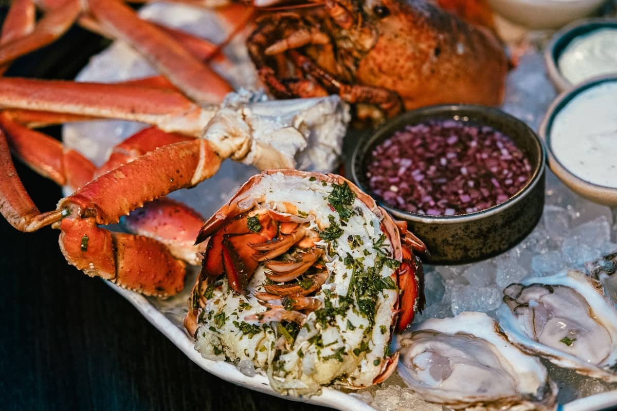 Nahaufnahme einer Meeresfrüchteplatte mit Dungeness-Krabbenbeinchen, Hummer, Austern und Soßen auf Eis, die frische Meeresfrüchte aus dem Pazifik präsentiert.