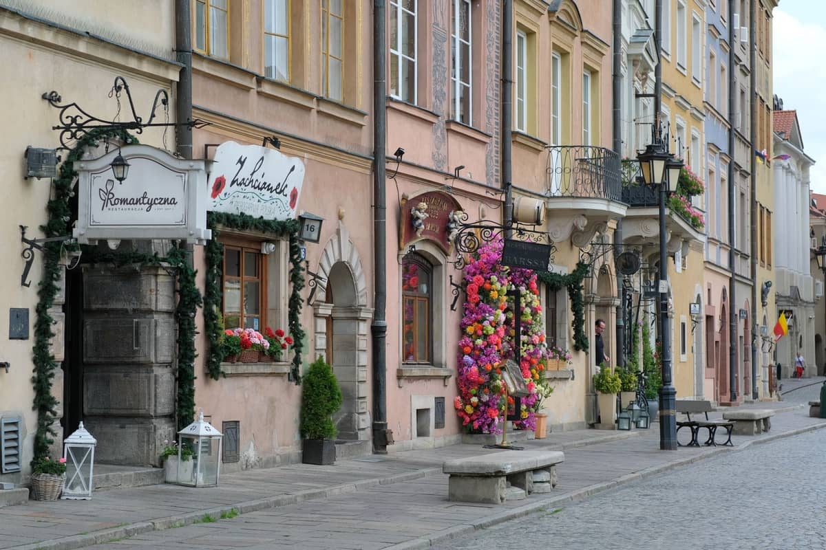 Charmante rangée de cafés et restaurants avec des décorations florales sur une rue pavée dans la Vieille Ville de Varsovie