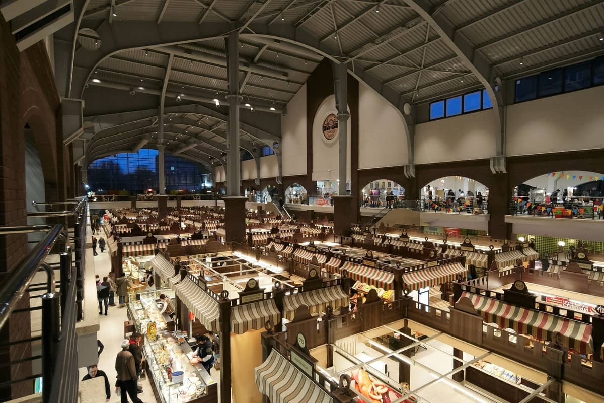 Intérieur d'un grand marché animé avec des rangées d'étals de nourriture et des gens qui font leurs courses à Varsovie.