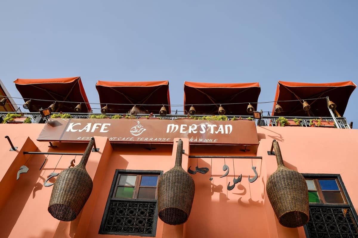 ด้านนอกของ Kafe Merstan ใน Marrakech Medina พร้อมที่นั่งบนเทอเรสและตะกร้าแขวนแบบดั้งเดิมบนผนัง