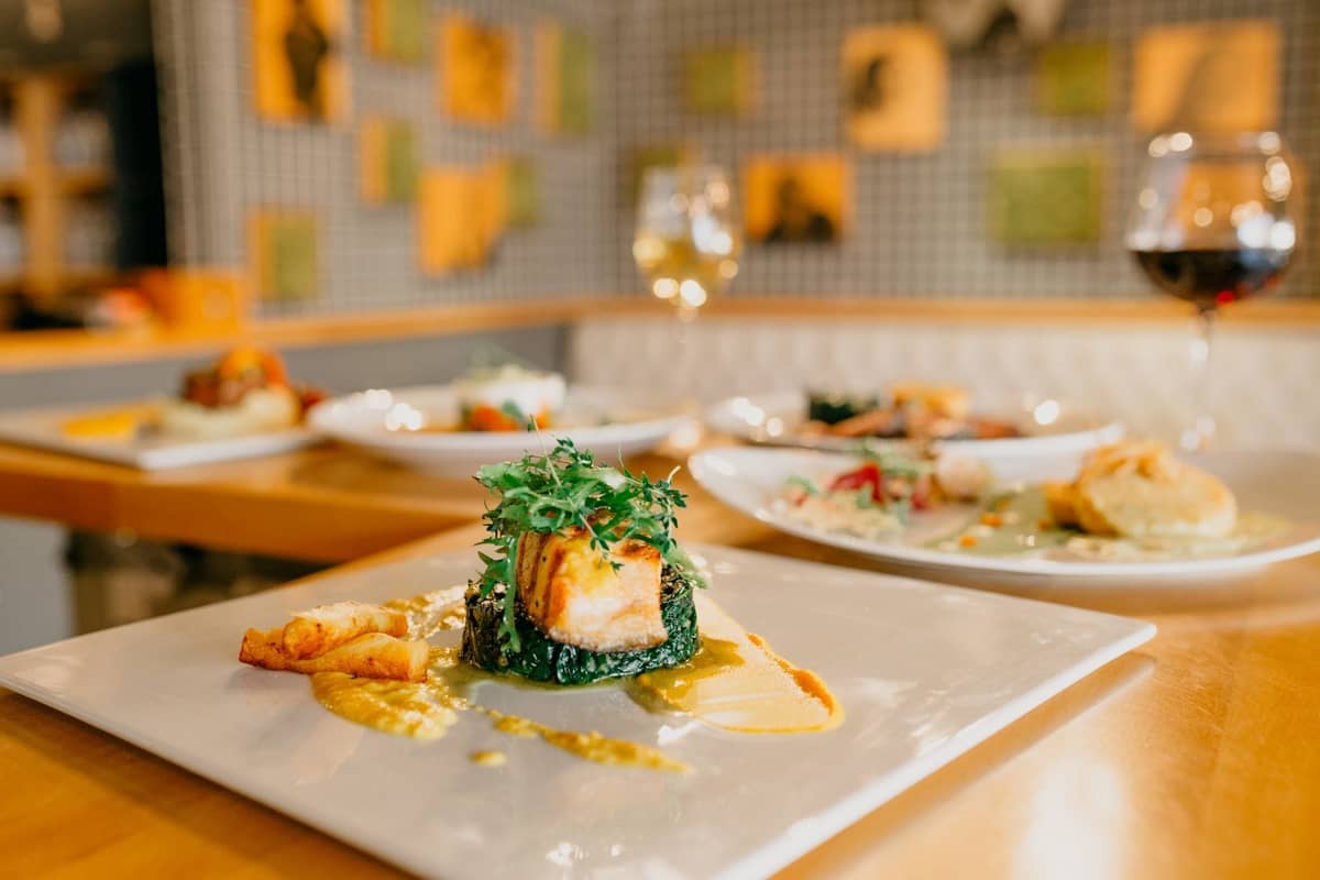 Plato elegante en un restaurante refinado con copas de vino y decoración contemporánea, ideal para una experiencia de alta gastronomía.