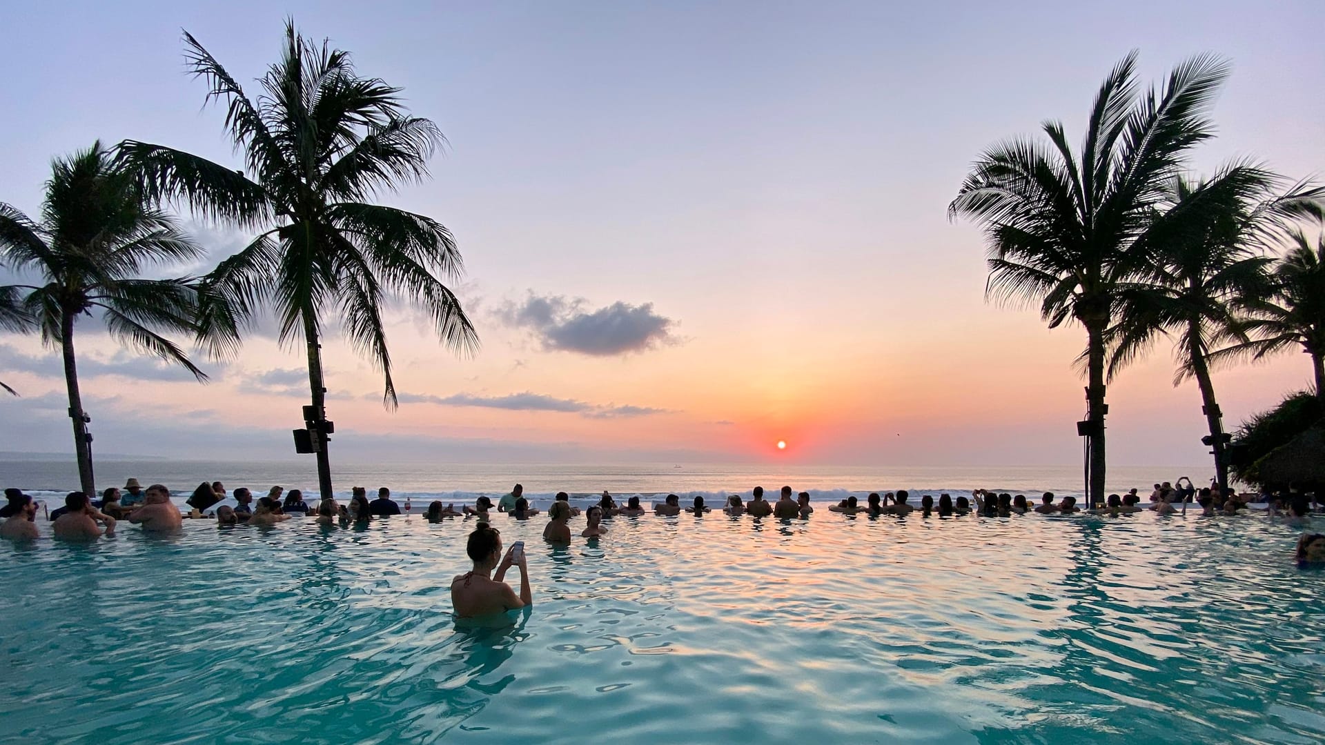 Sonnenuntergang in einem Beachclub in Seminyak auf Bali mit Infinity-Pool und Meerblick