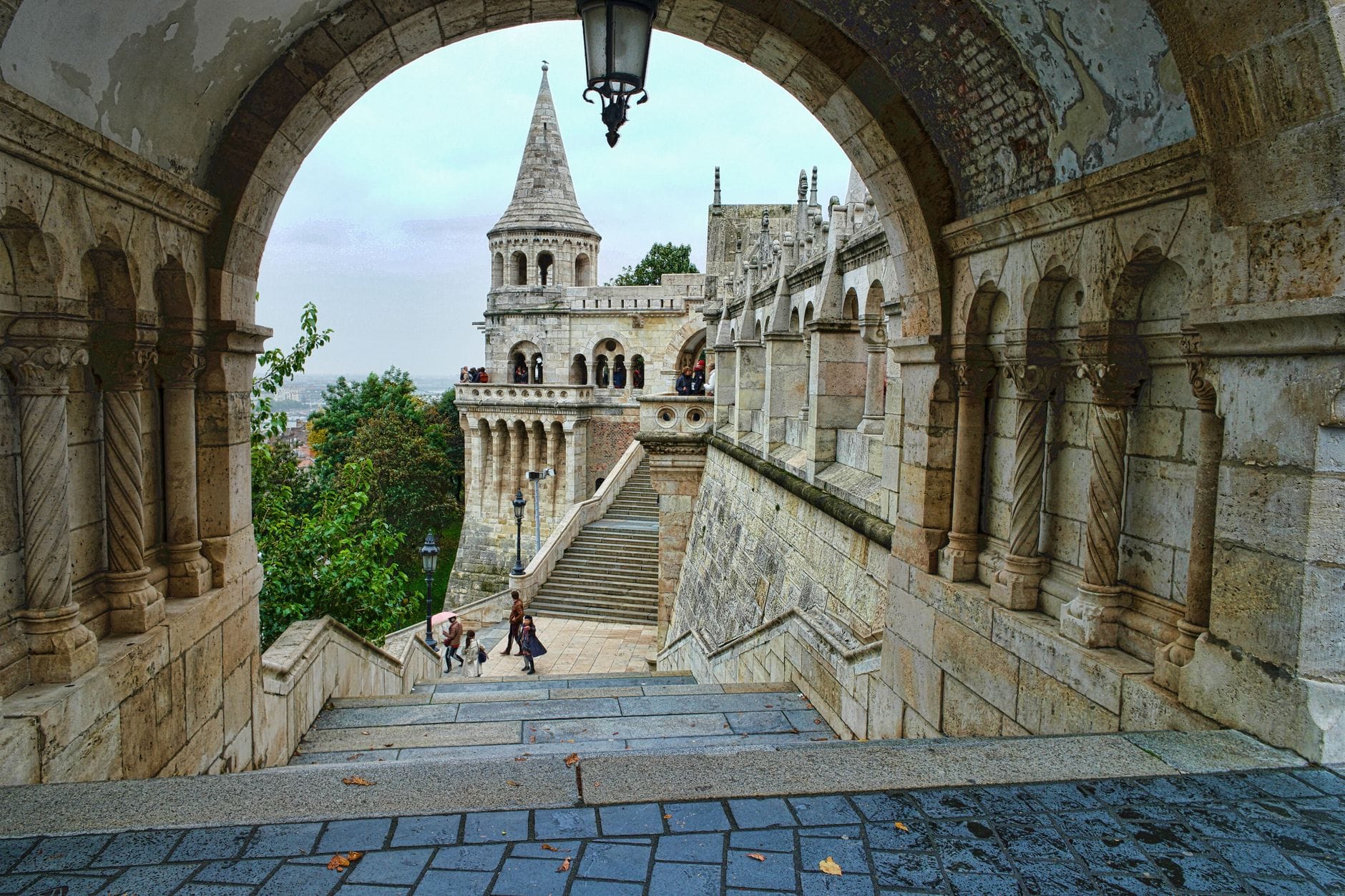 Steinbogen, der den Blick auf die Fischerbastei mit ihren Türmen und der Treppe im historischen Burgviertel von Budapest rahmt.