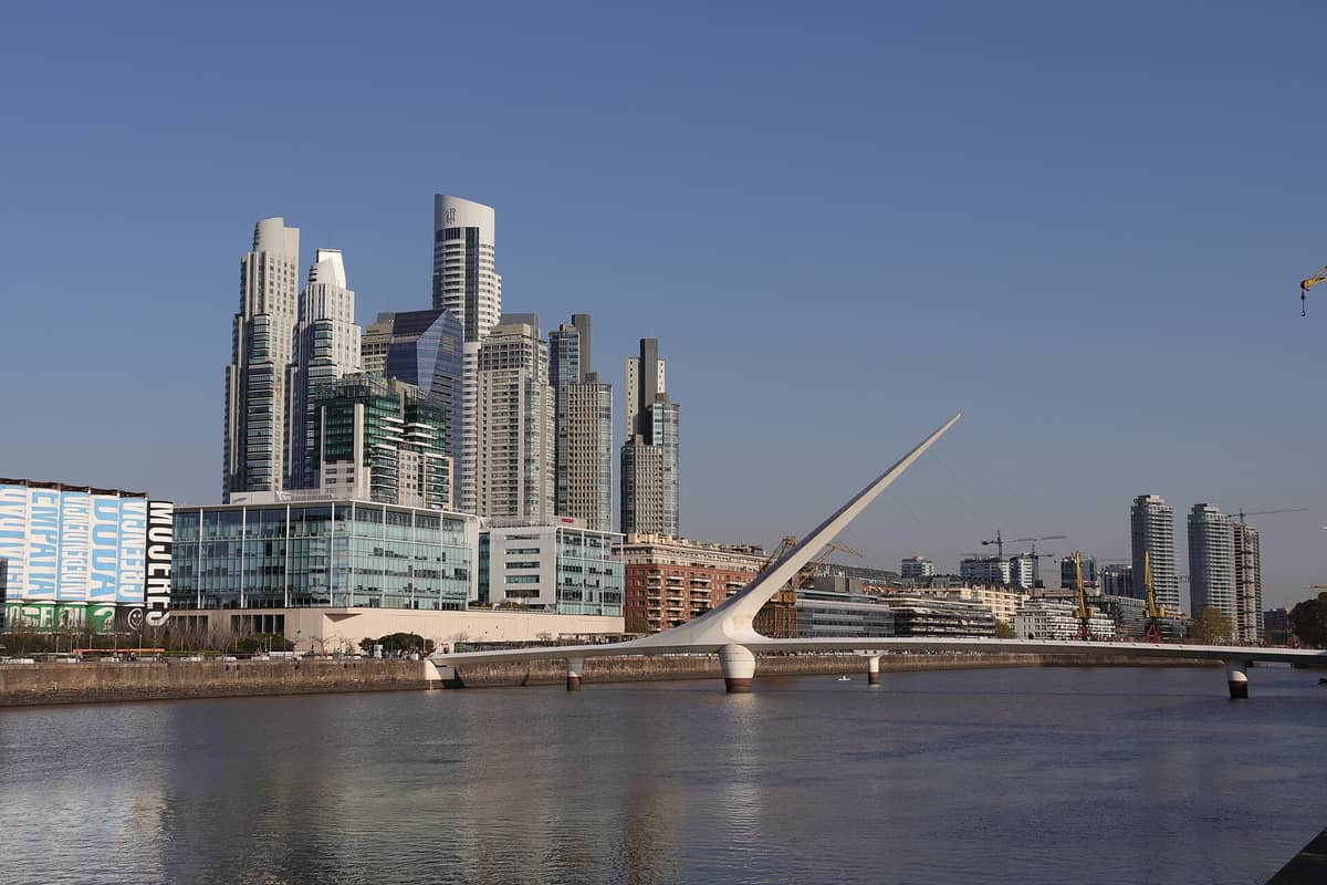 วิวกว้างของ Puerto Madero ที่แสดงให้เห็นอาคารสูงระฟ้าหรูหราและสะพาน Puente de la Mujer สมัยใหม่เหนือแม่น้ำ