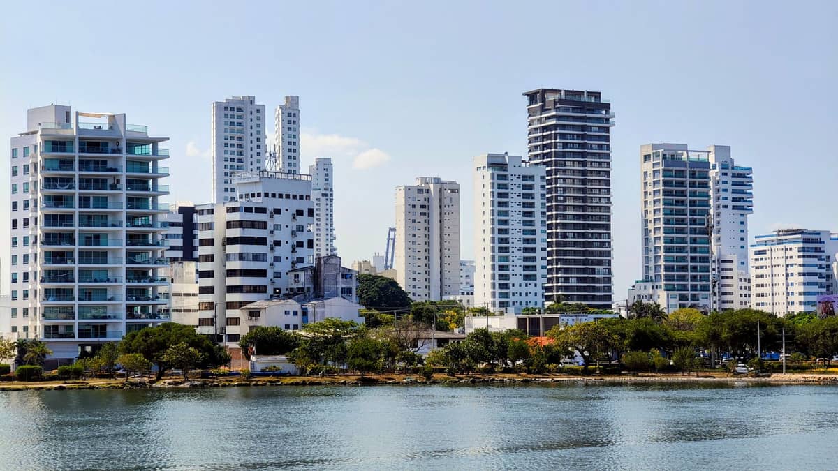 Modern apartment buildings in a peaceful, low-density area by the waterfront with trees and calm street, likely Manga in Cartagena, Colombia.