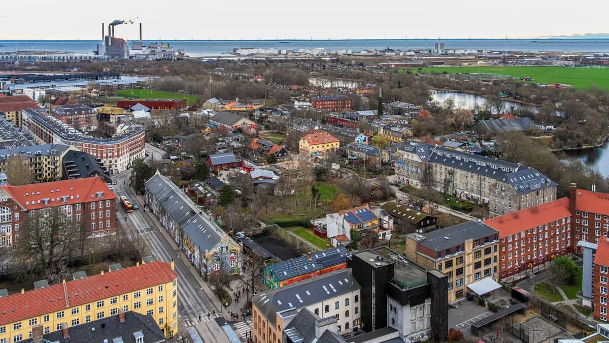 Luftaufnahme von Christianshavn in Kopenhagen mit bunten Gebäuden, Grünflächen, Kanälen und dem Hafen im Hintergrund.