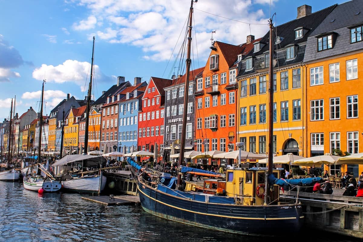 Bunte historische Gebäude und angedockte Boote entlang des Nyhavn-Kanals im Zentrum von Kopenhagen an einem hellen Tag.