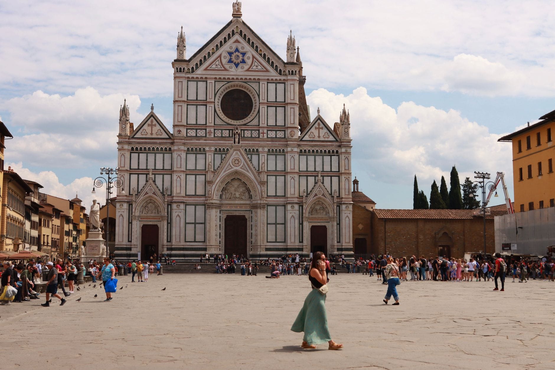 วิวกว้างของ Piazza Santa Croce พร้อม Basilica di Santa Croce และผู้คนที่เดินอยู่ด้านหน้าในวันที่แดดสดใส