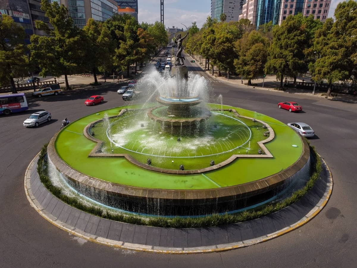 Luftaufnahme eines großen modernen Kreisverkehrs mit einem zentralen Brunnen, umgeben von Bäumen und städtischen Gebäuden in Guadalajara.