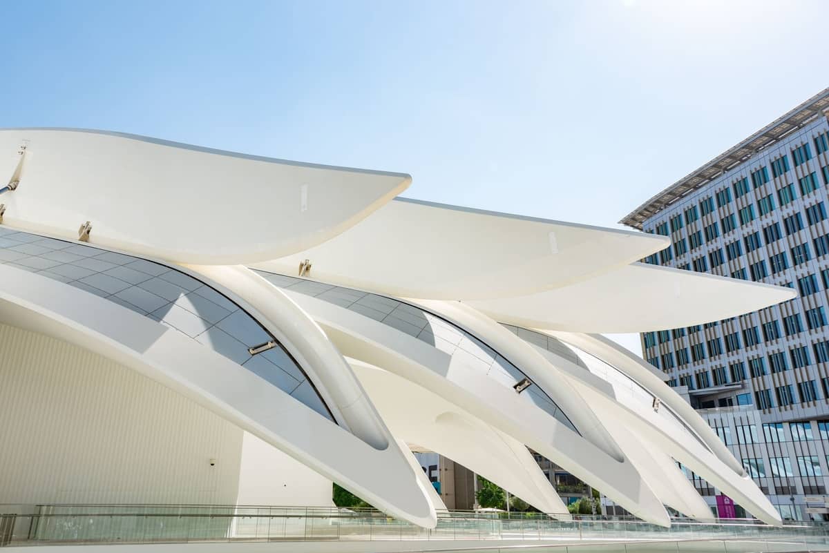 Zeitgenössisches weißes Architekturgebäude mit geschwungenen Dachlinien, neben einem modernen Büroturm unter klarem blauem Himmel in Guadalajara