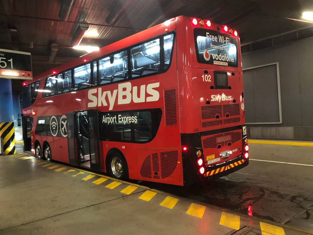 Roter SkyBus Airport Express-Bus an einem Terminalsteig in Melbourne, bereit zum Einsteigen der Fahrgäste, als Illustration der Flughafentransportlogistik.