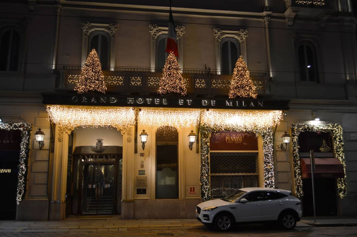 Extérieur du Grand Hotel et de Milan la nuit décoré de lumières élégantes avec une voiture garée devant