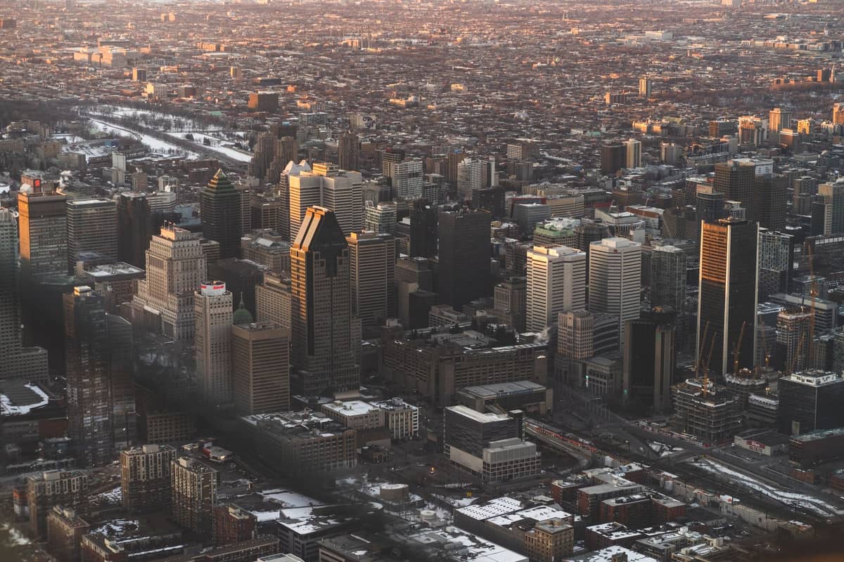 Luftaufnahme von Montreal mit der Skyline der Innenstadt, umgeben von weitläufigen Vierteln und der Stadtlandschaft bei Sonnenuntergang.