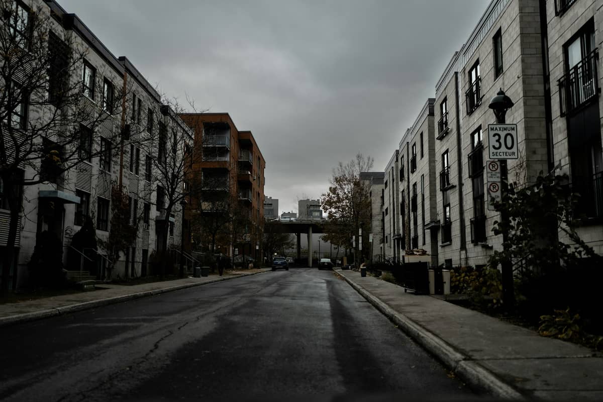 Moderne Eigentumswohnungsgebäude säumen eine ruhige Wohnstraße unter einem bewölkten Himmel in Montreal.