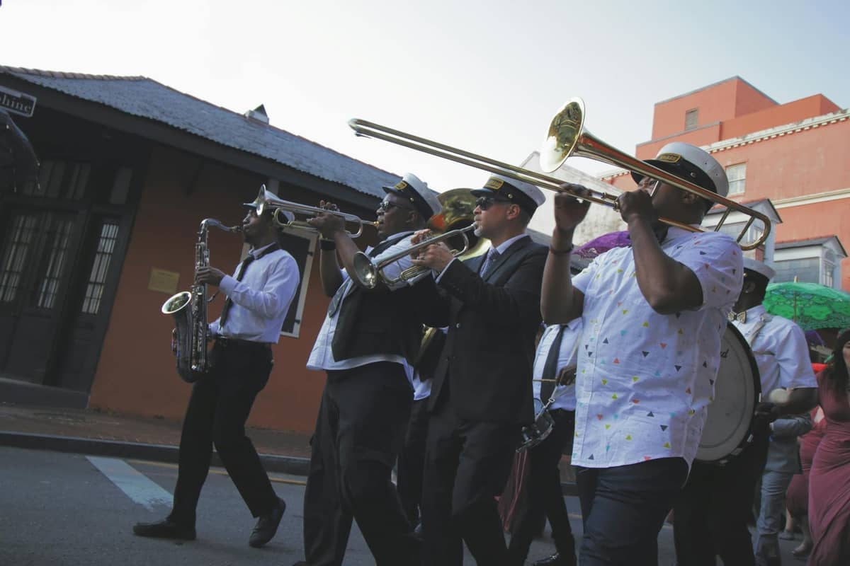 A lively New Orleans street scene with a jazz brass band marching and playing music, capturing the city’s vibrant musical culture.