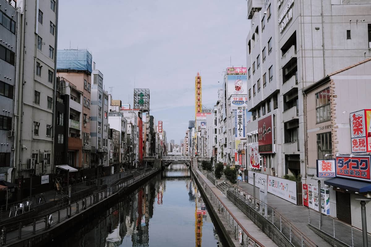 Daytime view of Osaka's Dotonbori canal lined with tall buildings and colorful signs, showing one of the city’s most iconic areas for visitors to stay.
