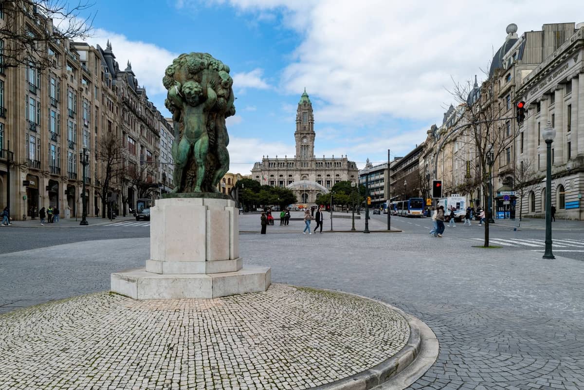 Weitwinkelansicht der Avenida dos Aliados im Zentrum von Porto mit einer Statue im Vordergrund und dem Rathaus im Hintergrund.
