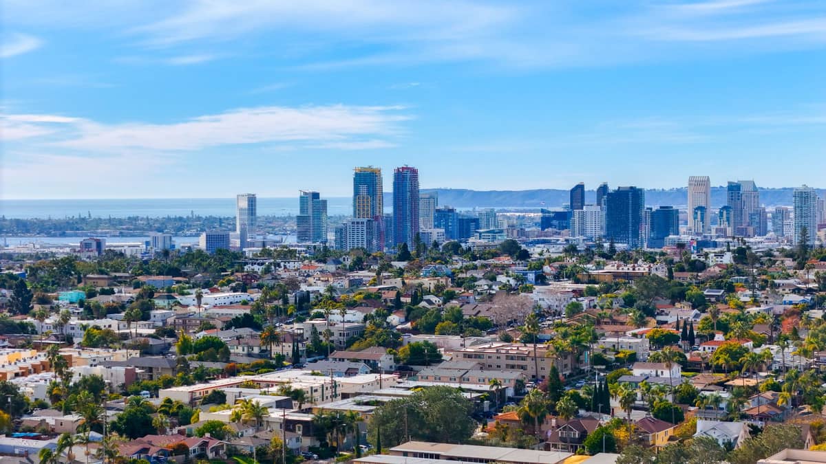 Panoramablick auf San Diego mit Wolkenkratzern der Innenstadt, Wohnvierteln und dem Pazifik in der Ferne unter blauem Himmel.