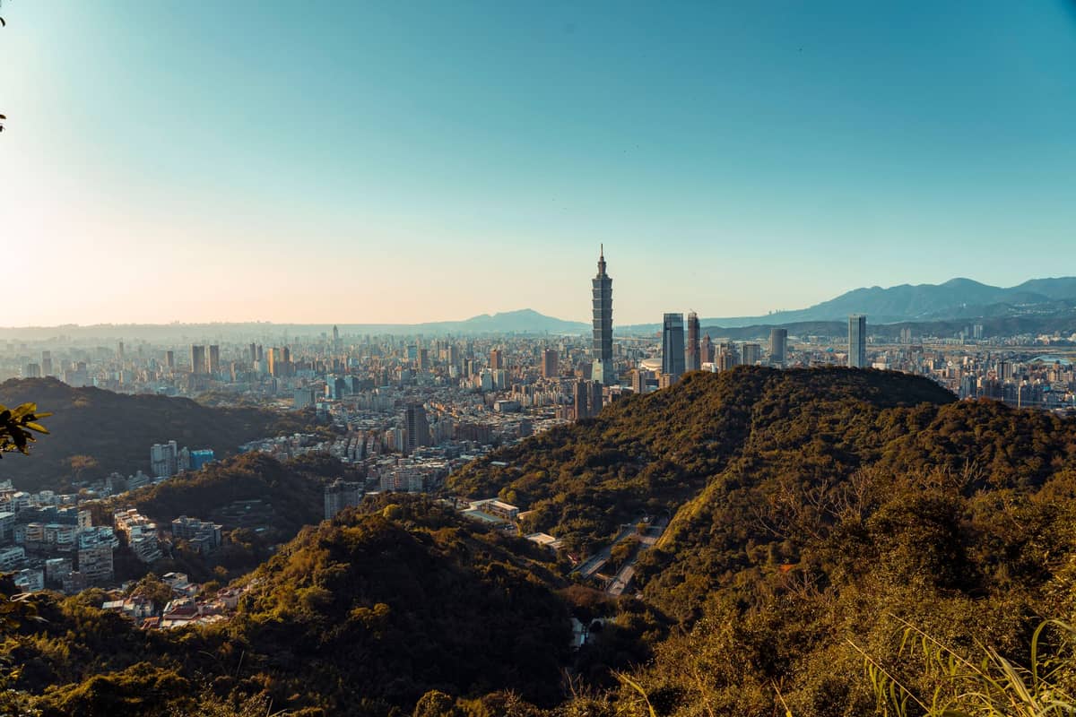 วิวกลางวันแบบกว้างเหนือเมืองไทเปพร้อม Taipei 101 การขยายตัวของเมือง และภูเขาโดยรอบที่แสดงให้เห็นผังแอ่งกระทะของเมือง