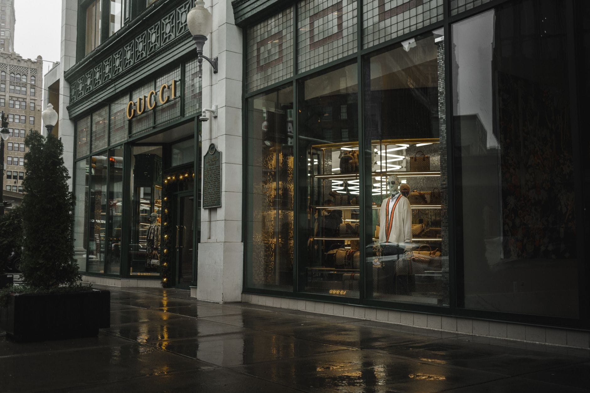 Fachada luxuosa da Gucci com manequins e uma elegante vitrine em uma rua molhada, evocando o luxo de Yorkville em Toronto.