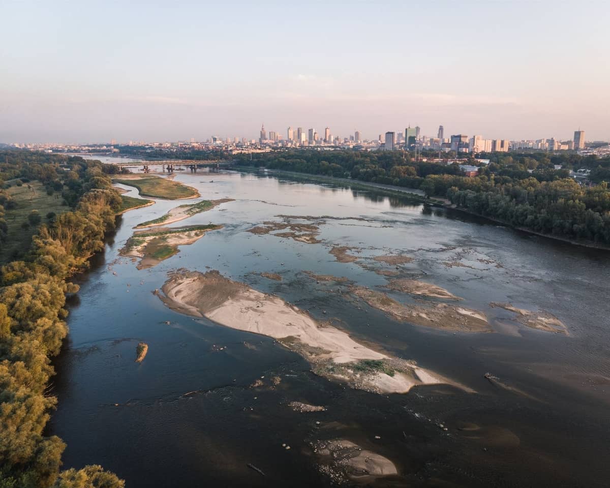Vista aérea del horizonte de Varsovia con el río Vístula dividiendo zonas verdes y edificios urbanos en ambas orillas.