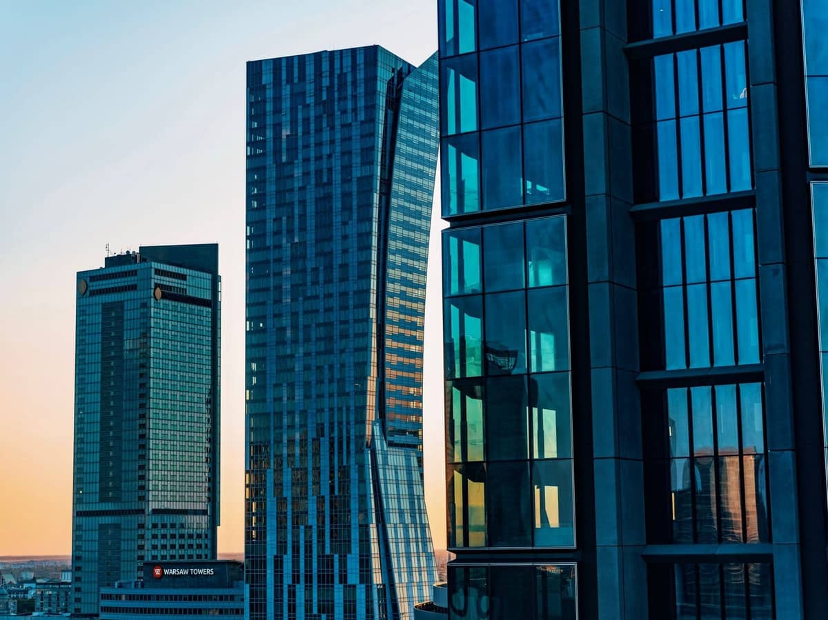 Modernos rascacielos de cristal al atardecer en el distrito de Wola de Varsovia, incluyendo la Varso Tower, con reflejos y una clara atmósfera de distrito financiero.