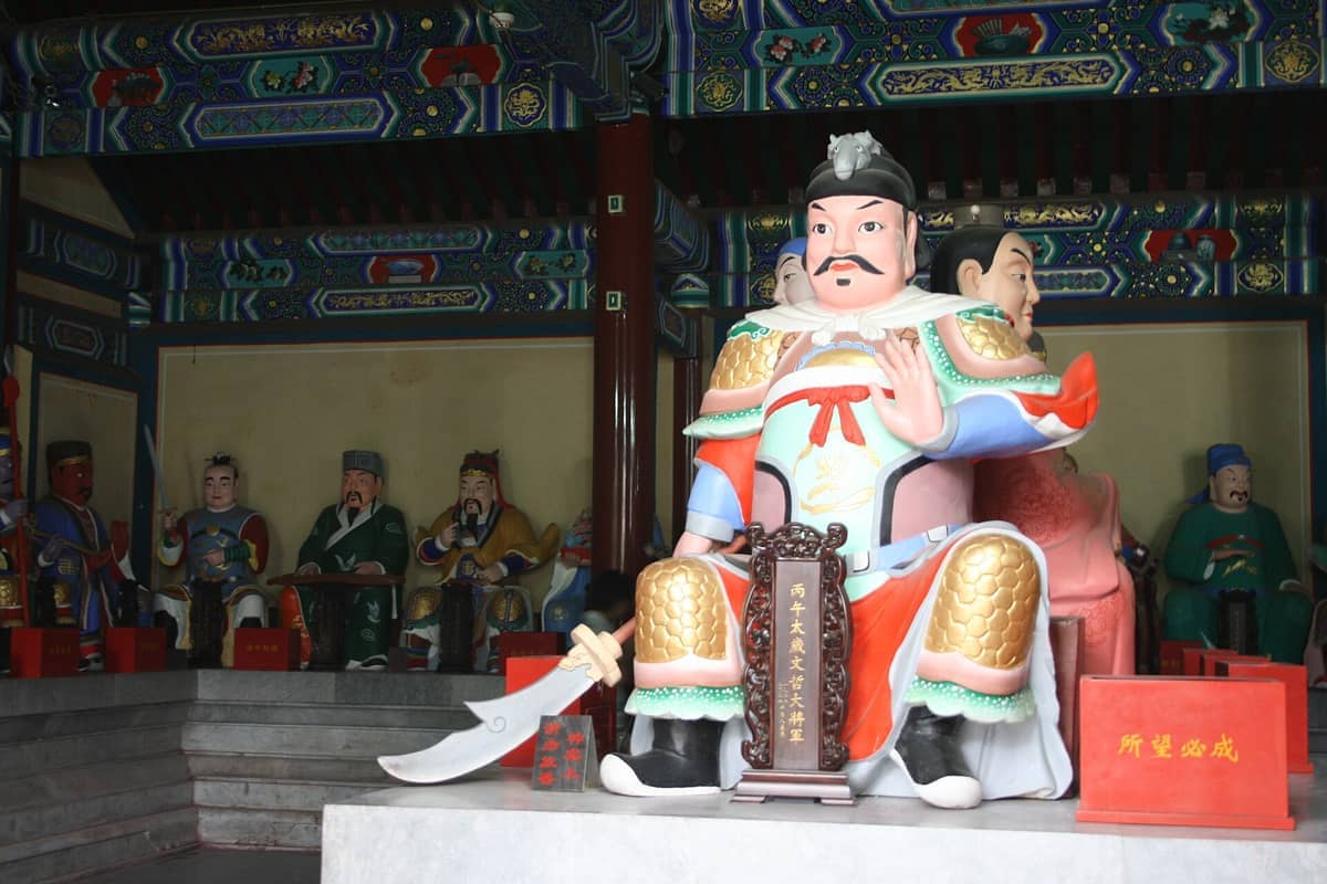 Farbenfrohe daoistische Statuen in kunstvollen Zeremonialgewändern in einem reich dekorierten Saal des White Cloud Temple, Peking.