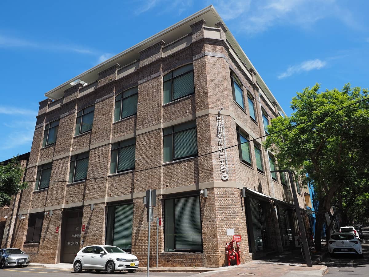 Außenansicht des markanten Backsteingebäudes der White Rabbit Gallery an einem sonnigen Tag in Chippendale, Sydney, mit gut sichtbarer Beschilderung und Straßenperspektive.
