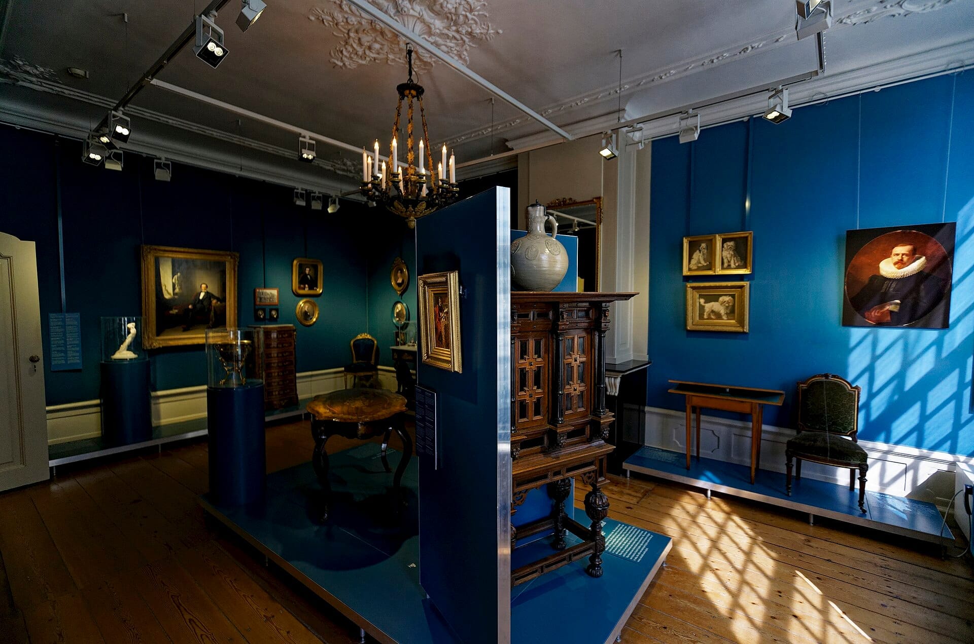 Interior del Museo Willet-Holthuysen con una galería de paredes azules con muebles antiguos, pinturas clásicas, esculturas e iluminación elegante de araña.