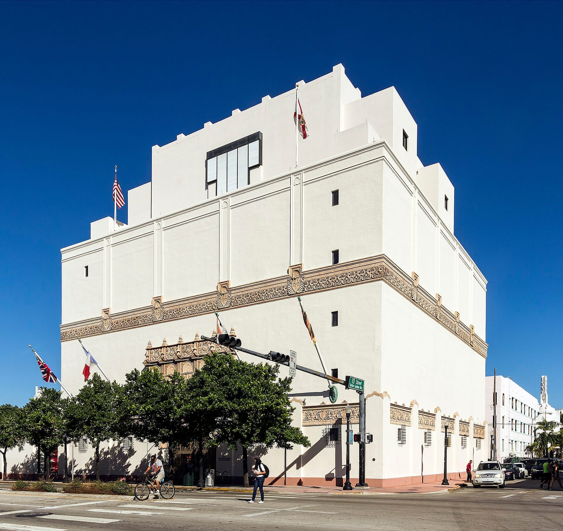 Esterno del museo Wolfsonian–FIU a Miami Beach, con la sua architettura bianca in stile Revival Mediterraneo, bandiere e un cielo azzurro soleggiato.
