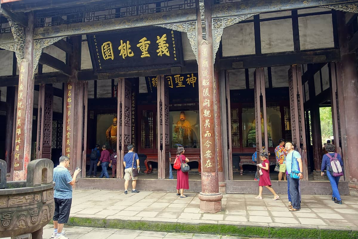 Mga bisitang nakatayo sa harap ng pangunahing bulwagan na may mga rebulto at kaligrapiyang Tsino sa Wuhou Shrine sa Chengdu, isang makasaysayang lugar mula Three Kingdoms era.