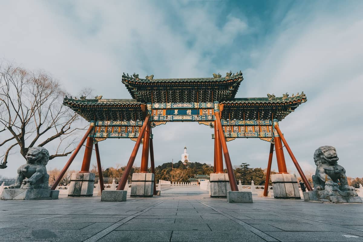 Traditionelles chinesisches Tor im Beihai-Park mit der weißen Dagoba-Pagode im Hintergrund, Bezirk Xicheng, Peking.
