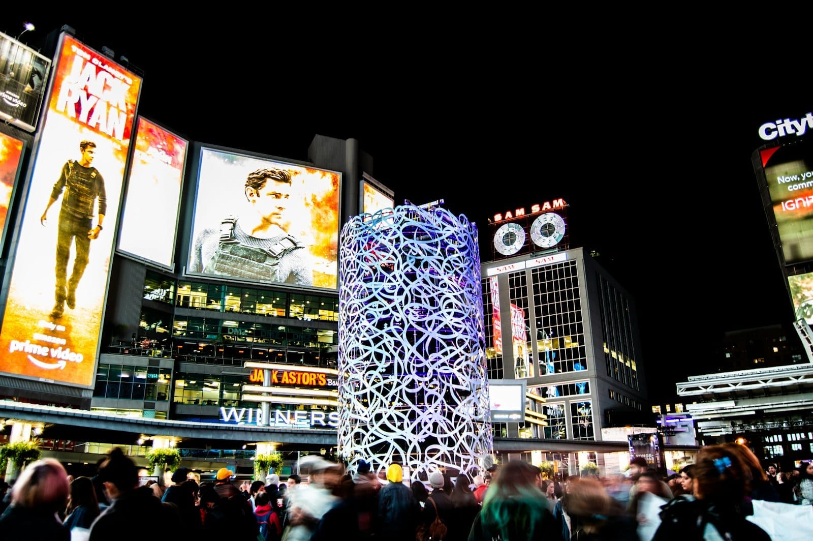 บรรยากาศกลางคืนที่ลานซังโกฟา (ชื่อเดิม Yonge-Dundas Square) โตรอนโต กับไฟสว่างไสว จอป้ายดิจิทัลขนาดใหญ่ ฝูงชน และชีวิตเมืองที่คึกคัก